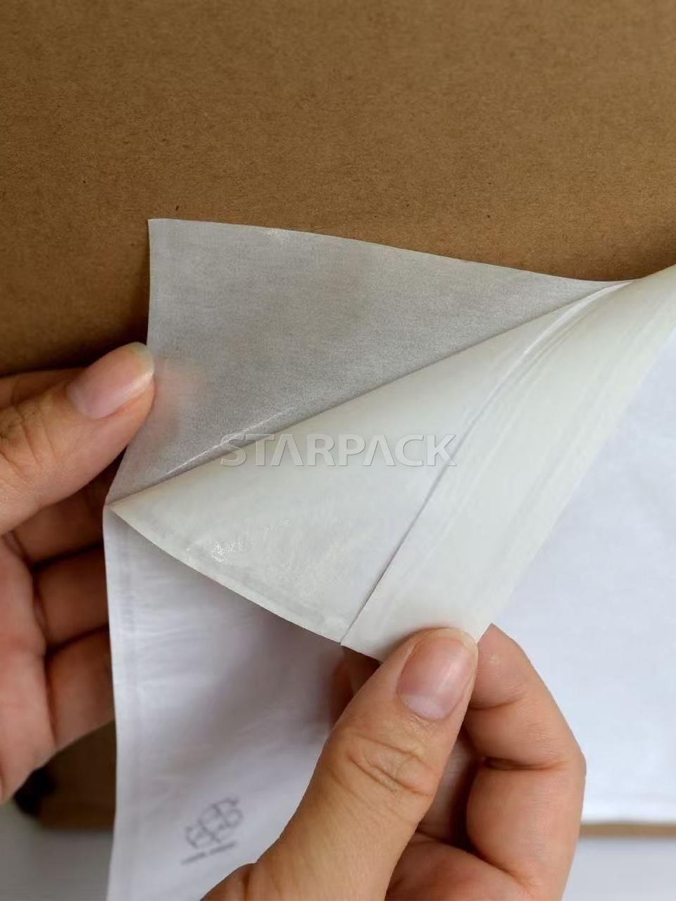 Hand flipping demonstration of compostable kraft paper self-adhesive document pouch, showing strong back glue and paper texture, plastic-free eco label pouch for warehouse shipping carton use